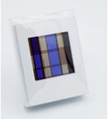 A clear acrylic picture frame holding a white mat with a central abstract geometric print in shades of blue, brown, and beige, shown on a light gray background.