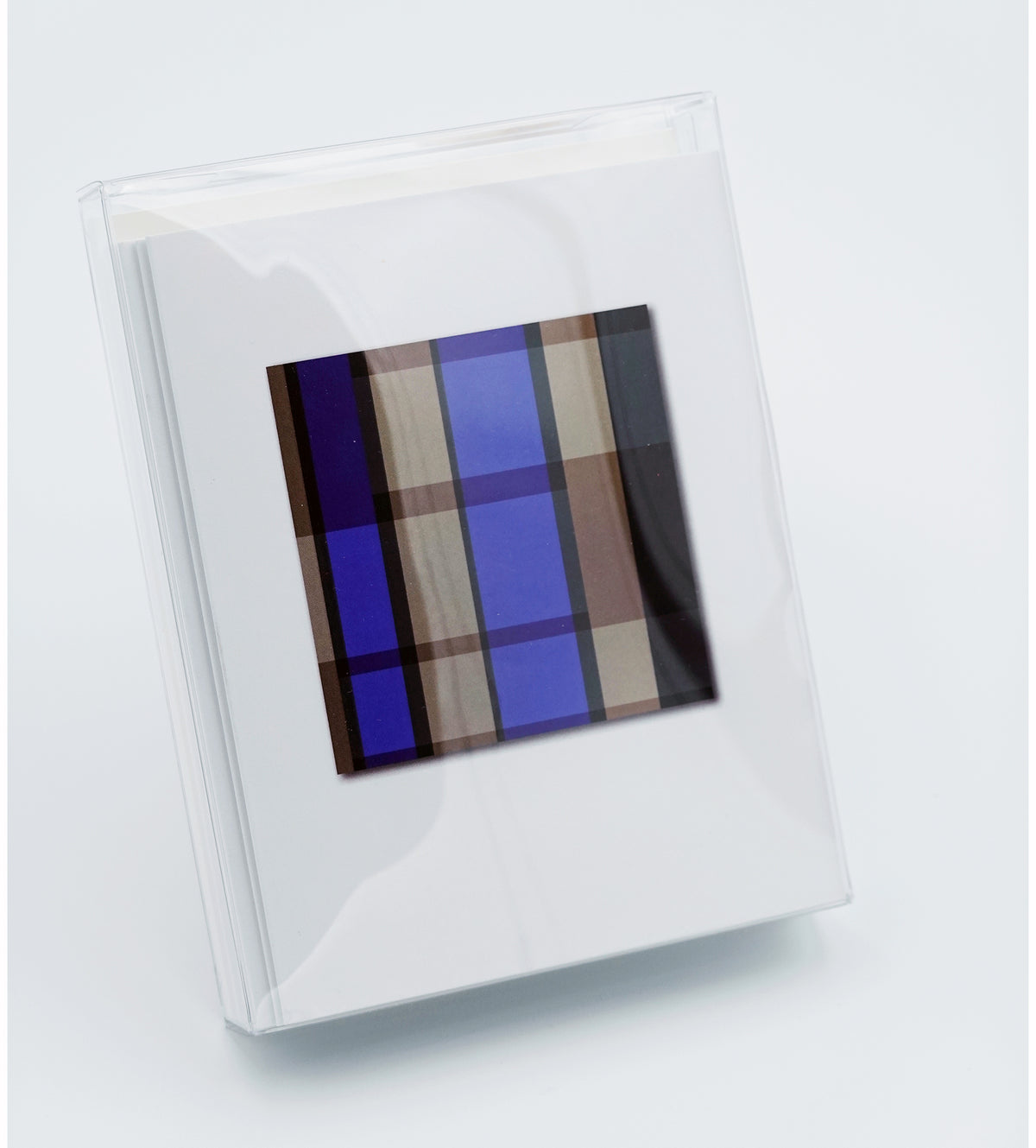 A clear acrylic picture frame holding a white mat with a central abstract geometric print in shades of blue, brown, and beige, shown on a light gray background.